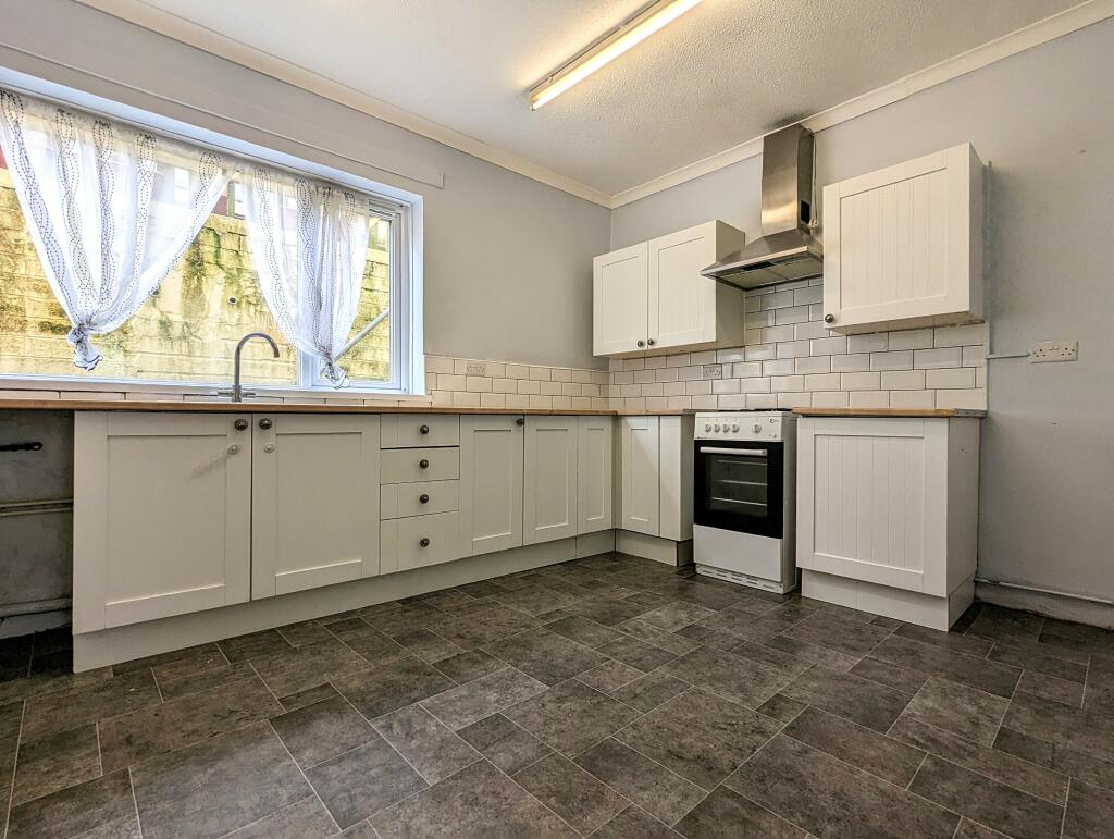 Kitchen after refurbishment — fitted units, tiled splashback, finished floor